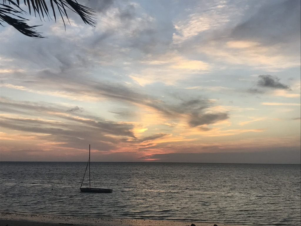 a single boat with the sun setting in the background